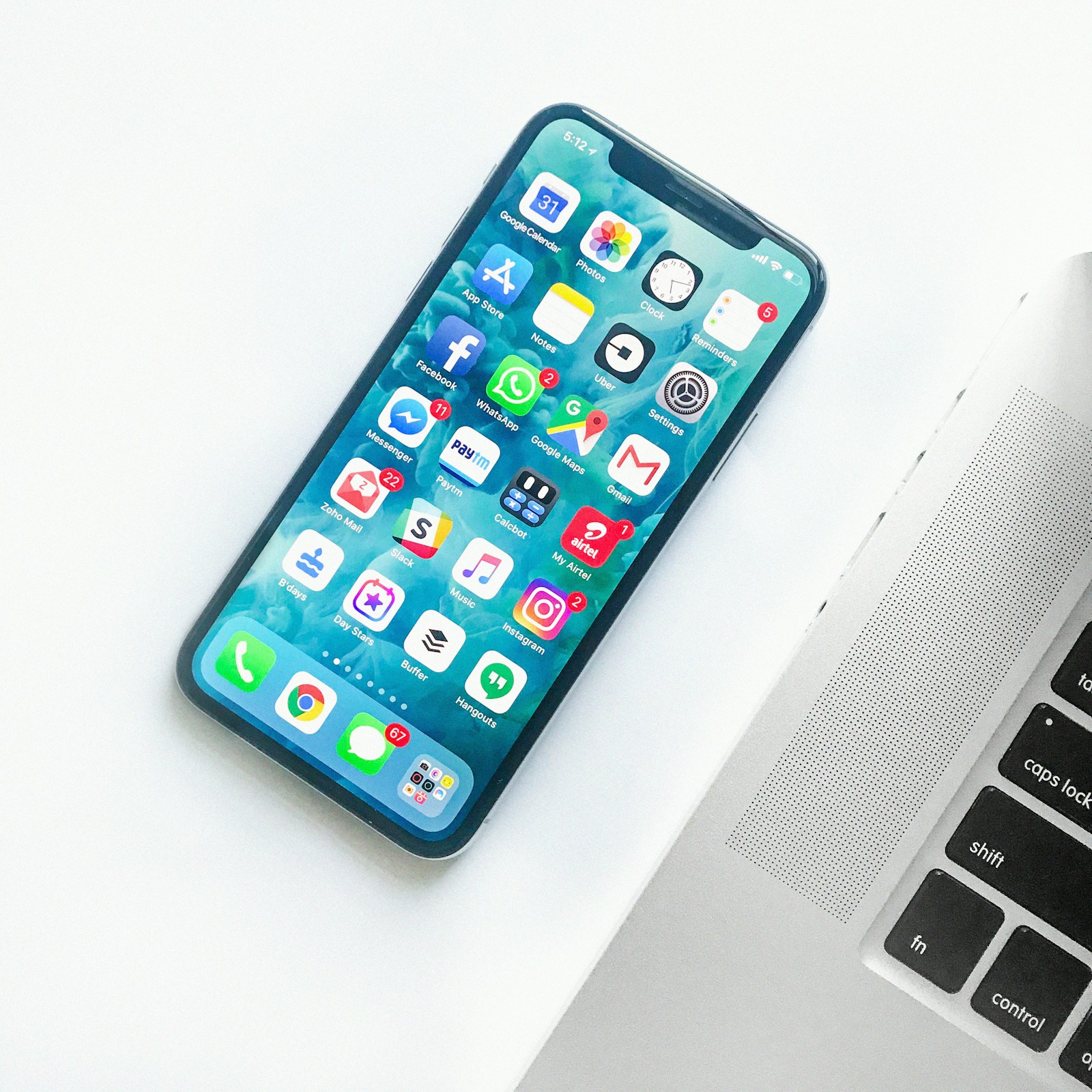 Hand holding an iPhone displaying the home screen against a blurred outdoor background