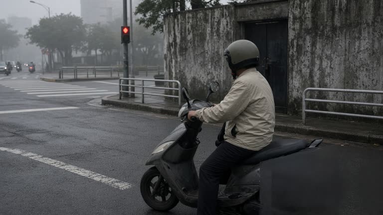 Taipei morning street with a scooter rider in open-face helmet and light jacket at a red light, humid haze, worn asphalt, no logos or readable text on products or signs