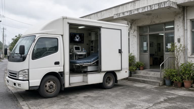 White mobile medical screening van parked outside a northern Taiwan community clinic with an ultrasound monitor visible through an open side door, overcast daylight, no logos or readable text