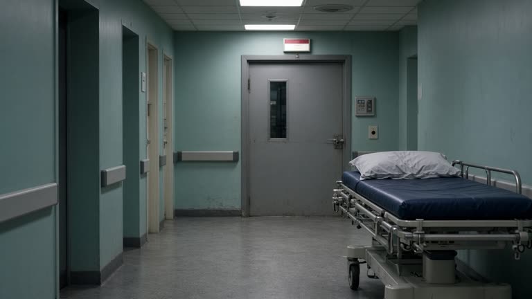 Hospital radiology corridor with a closed MRI suite door and wheeled gurney, cool fluorescent light, muted teal walls, no logos or readable text.