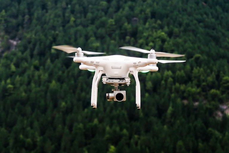 Silhouette of a small quadcopter drone against a cloudy sky