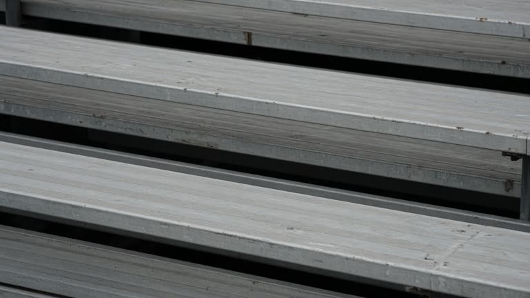Empty scuffed wooden bleacher plank in overcast daylight, no people, no logos, no readable text