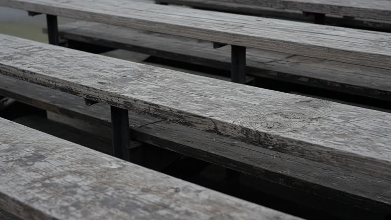 Empty scuffed wooden bleacher plank in overcast daylight, no people, no logos, no readable text