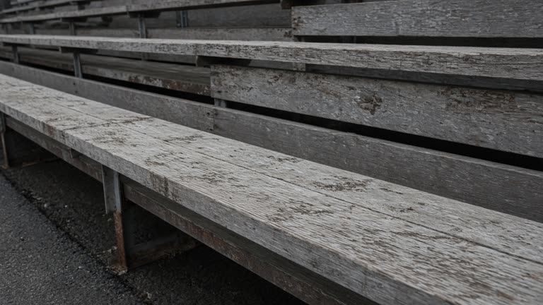 Empty scuffed wooden bleacher plank in overcast daylight, no people, no logos, no readable text