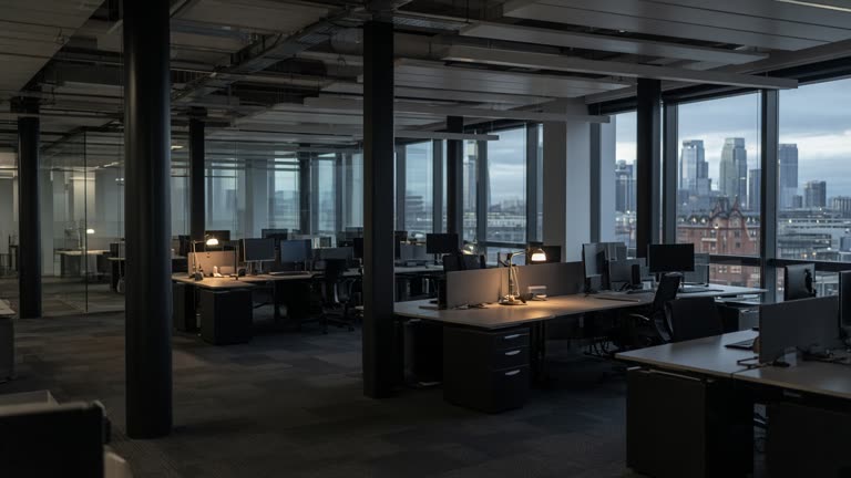 Canary Wharf trading floor aisle with FX option volatility tiles on overhead monitors and empty swivel chairs, grey daylight through windows, no logos or readable text