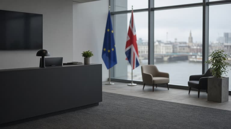 Glass-fronted think-tank office overlooking the Thames on an overcast morning, EU and UK flags blurred in background, empty reception, no logos or readable text