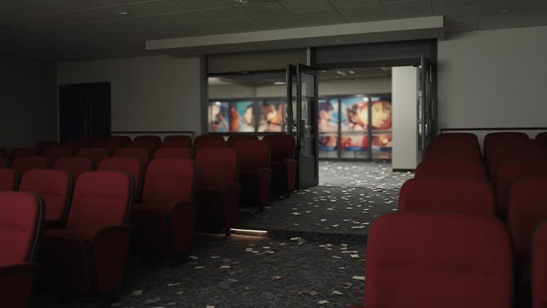 Japanese movie theatre auditorium with red seats and dim aisle lighting, blurred anime-style poster panels in lobby glass beyond doors, scattered ticket stubs on carpet, no logos or readable text