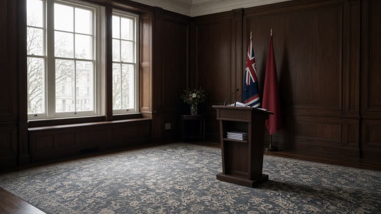Empty UK Foreign Office briefing room with dark wood paneling, muted flags without readable names, lectern microphone and stacked briefing folders, overcast daylight through tall windows, no logos or readable text