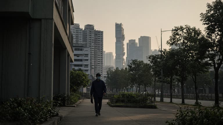 Photoreal morning scene in Singapore's Central Region: a hazy skyline of HDB blocks and office towers in soft amber-grey light, a pedestrian in a mask walking along a covered walkway, distant hills softened by smoke haze, shot on a 35mm lens at eye level, no logos or readable text