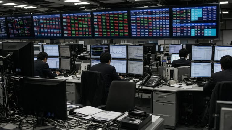 Traders at electronic boards in a Tokyo brokerage hall with yen bond yields highlighted on overhead screens