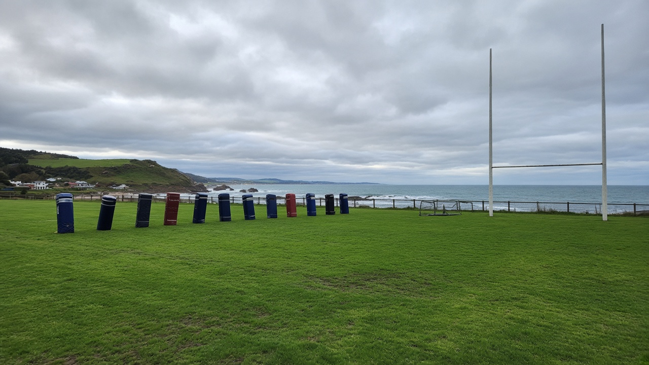 Empty rugby league training field with tackle bags and goal posts on an overcast coastal afternoon, no players faces, no logos or readable text