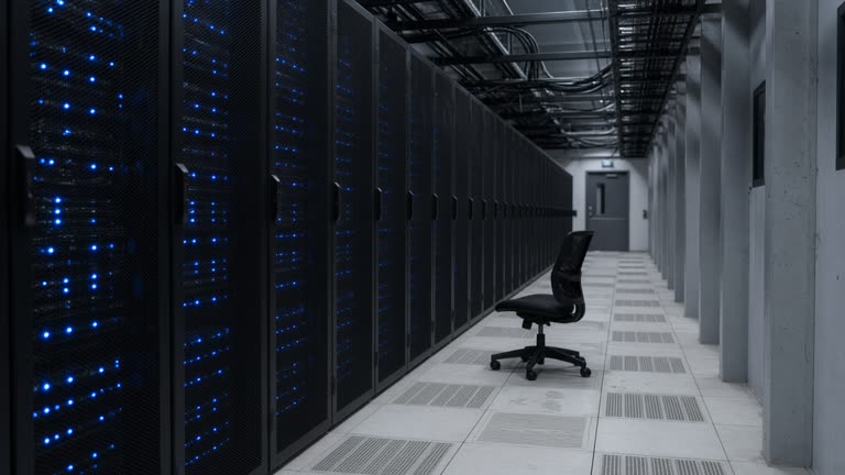Data center cold aisle with blue LED rack lights, raised floor tiles, cable trays overhead, empty rolling chair, no logos or readable text
