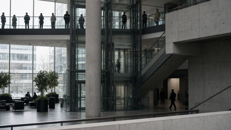 London fintech office atrium with glass lifts and people silhouettes on a mezzanine, overcast daylight through windows, matte concrete and steel, no logos or readable text on screens or signage