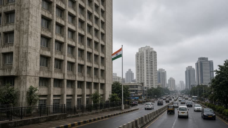 Mumbai financial district office tower exterior at overcast midday with monsoon-stained concrete and distant commuter traffic, small Indian flag on pole without readable signage on building facades, no logos or readable text