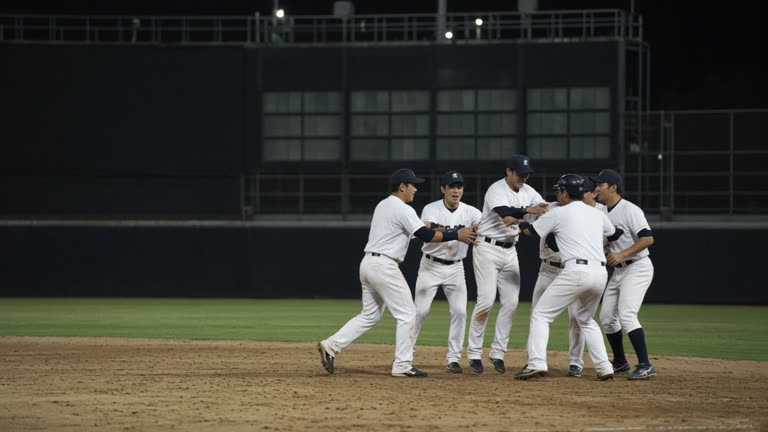 Night baseball game in a Taiwan stadium with players celebrating near home plate and a lit scoreboard in the background, no logos or readable text