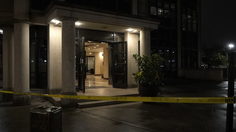 Photoreal night scene outside a downtown mosque entrance at a commercial tower after a small fire, with police cordon tape, an oil tin on the pavement, and no people's faces, no logos or readable text