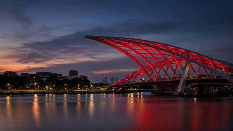 Singapore city bridge at dusk with red architectural lighting on steel structure, reflections on water, long exposure documentary style, no logos or readable text