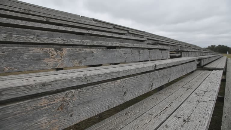Empty scuffed wooden bleacher plank in overcast daylight, no people, no logos, no readable text