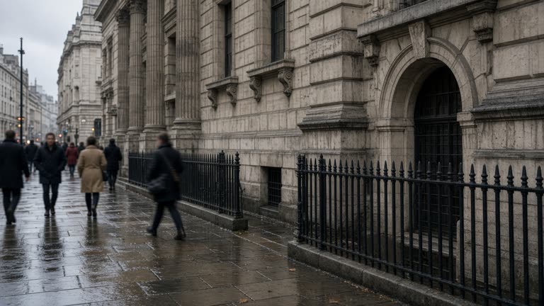 Exterior of the Bank of England on Threadneedle Street on an overcast morning, stone facade and black railings, commuters passing on wet pavement, no logos or readable text