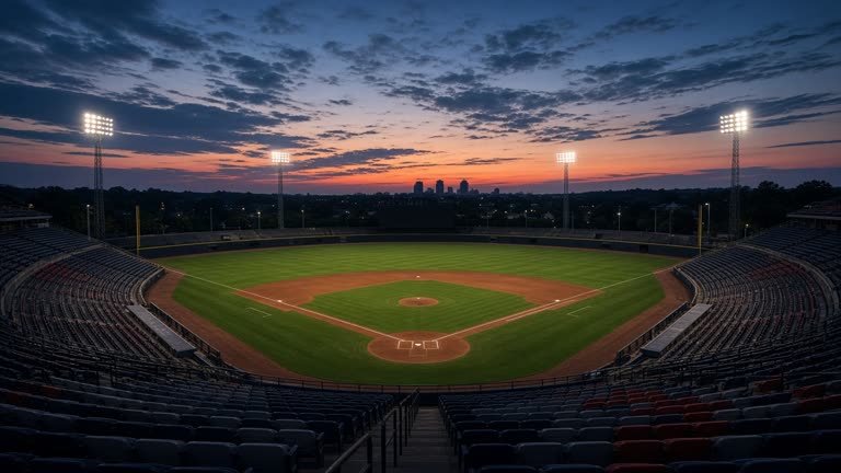 An empty professional baseball stadium at twilight with freshly raked infield dirt, outfield lights powering on, seats in muted team colors without logos, no readable text on the scoreboard.