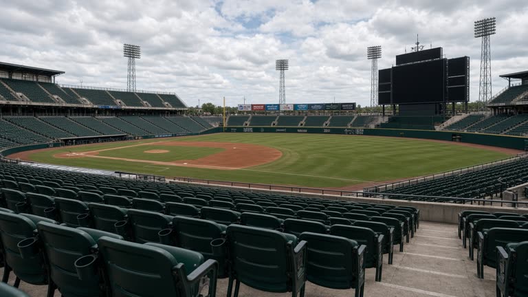 Outdoor baseball stadium stands with green seats and empty diamond under cloudy afternoon light, scoreboard blank with no logos or readable text