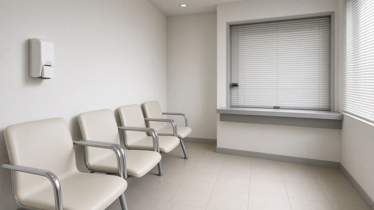 Dermatology clinic waiting area with plastic chairs, a wall-mounted hand sanitizer dispenser, closed reception window, soft daylight from blinds, no readable posters or logos.